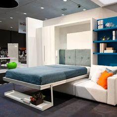 a bed sitting in the middle of a room next to a couch and book shelf