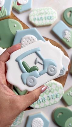 a hand holding a decorated cookie in the shape of a tractor