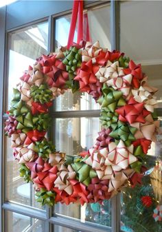 a wreath hanging on the front door with red and green bows attached to it's sides