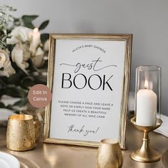 a sign that says guest book next to some candles and flowers on a gold table