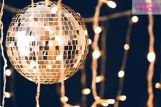 a disco ball hanging from strings with lights in the background