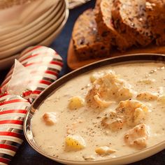 a bowl filled with soup next to some bread on top of a blue table cloth