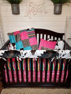 a baby crib with pink and blue pillows on it