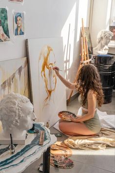 a woman sitting on the floor in front of some paintings