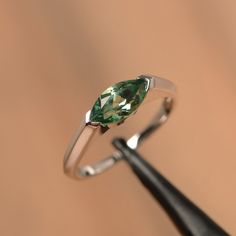 It is a green sapphire ring. The main stone is 5 mm*10 mm marquise cut.weight about 1.34 carats. The basic metal is sterling silver and plated with rhodium/14k white gold/14k rose gold/14k yellow gold You can also go to my shop Home for more elegant rings: https://www.etsy.com/shop/godjewelry?ref=hdr_shop_menu Customization is always welcome and please feel free to contact with me if you have any design ideas! Modern Marquise Cut Promise Ring Jewelry, Sterling Silver Solitaire Jewelry, Marquise Cut, Modern Jewelry With Prong Setting And Marquise Cut, Modern Jewelry With Marquise Cut And Prong Setting, Modern Marquise Cut Jewelry With Prong Setting, Modern Marquise Cut Gemstone Jewelry, Marquise Cut Emerald Promise Ring, Silver Marquise Emerald Ring, Modern Sterling Silver Marquise Jewelry