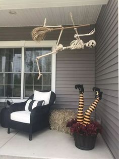 a skeleton sitting on top of a chair in front of a window next to a halloween decoration