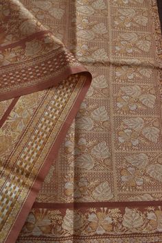 an orange and gold sari is laying on top of a wooden table with other items