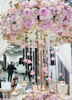 a table topped with lots of pink flowers next to a tall chandelier filled with candles