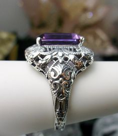 Natural Purple Amethyst Ring Intricate Design#149 Custom Made Inspired by Victorian era designs, I now offer this lovely filigree reproduction in sterling silver. This is a flawless natural purple amethyst is 12mm by 10mm in Length & Width. The ring is 3/4th of an inch North/South on the finger. The inside of the band is etched 925. Notice the intricate and detailed Victorian design of the antique patina silver filigree setting all the way down the band. This is an exquisite rendition of an Victorian Amethyst Ring With Accent Stones For Formal Occasions, Victorian Amethyst Ring With Center Stone As Gift, Amethyst Rings With Intricate Design For Wedding, Antique Purple Ring For Anniversary, Antique Purple Rings For Anniversary, Classic Amethyst Ring For Wedding, Elegant Purple Amethyst Ring With Filigree, Elegant Purple Amethyst Filigree Ring, Classic Silver Filigree Amethyst Ring