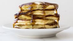 stack of pancakes covered in syrup on a white plate