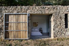 an open door leading to a bed in a stone building