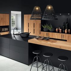 a black kitchen with wooden cabinets and stools