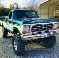 a green pick up truck parked in front of a building