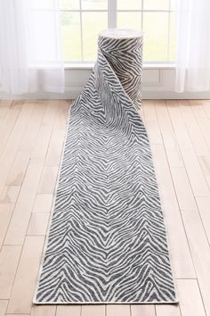 a zebra print rug on the floor in front of a window with white drapes