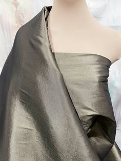 a mannequin's head wearing a silver dress with an asymmetrical neckline