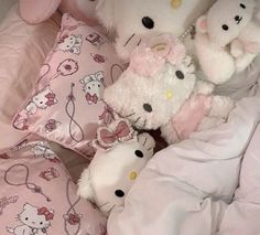 several hello kitty stuffed animals laying on top of a pink comforter in a child's bed