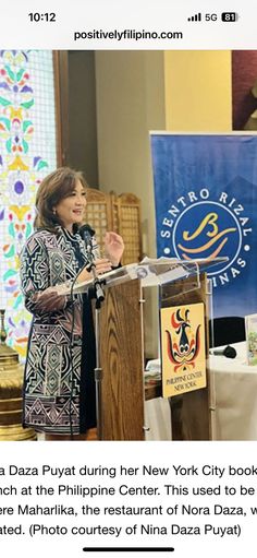 a woman standing at a podium in front of a banner