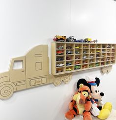 two stuffed animals are sitting next to a toy truck on the wall in a children's room