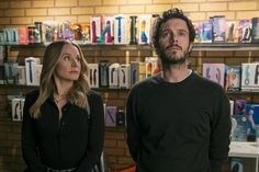 a man and woman standing in front of shelves with books