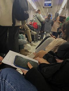 many people are sitting on the train and one person is holding a book in his hand