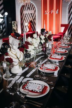 a long table is set with red and white plates, silverware, and candles