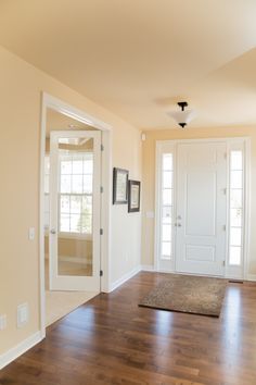 an empty living room with hard wood floors and white doors, framed pictures on the wall