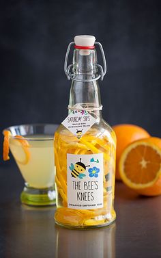 a glass bottle filled with liquid next to sliced oranges