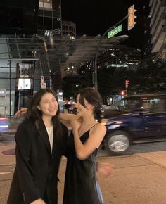 two women standing next to each other on a street