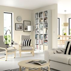 a living room filled with furniture and bookshelves next to a large open window