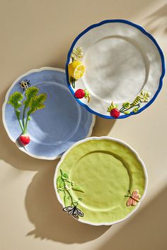 three plates sitting on top of a table next to each other with flowers painted on them