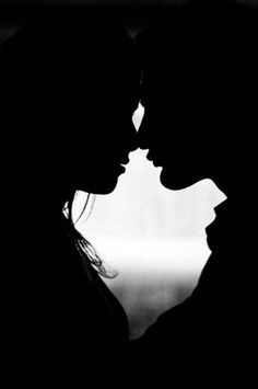 a couple kissing each other in black and white