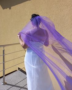 a woman in a white dress and purple veil