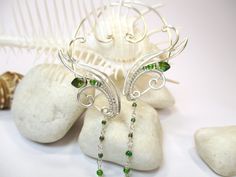 a pair of green beaded earrings sitting on top of a rock next to a sea shell