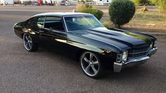 an old black car parked in a parking lot