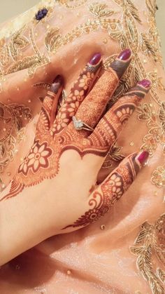 a woman's hand with henna tattoos on it and her hands resting on the ground