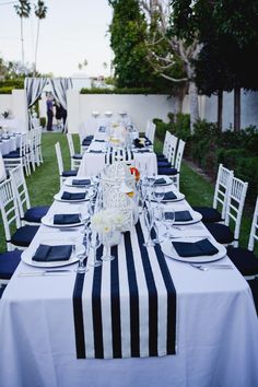 a long table is set with blue and white linens for an outdoor wedding reception