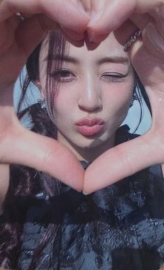 a woman making a heart shape with her hands