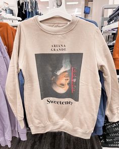 a sweater with an image of a woman's face hanging on a rack in a clothing store