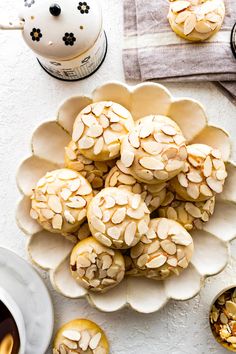 almond cookies in a bowl on a table next to other desserts and tea cups