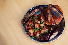 a plate with sausage, potatoes and other food items on it sitting on a wooden table