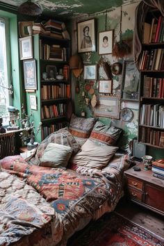 a bed with lots of pillows and blankets in a room filled with bookshelves