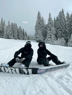 two snowboarders sitting in the snow with their boards