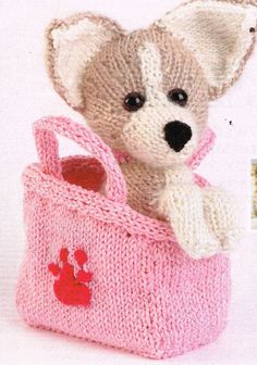 a small stuffed animal in a knitted pink bag with red paw prints on it