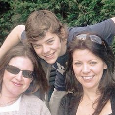 three people posing for the camera with trees in the background