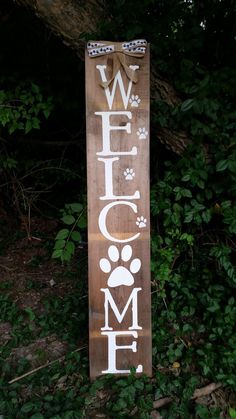 a wooden sign that says welcome home with paw prints