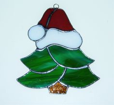 a stained glass christmas tree ornament with a santa hat on it's top