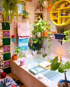 a bathtub with plants and towels hanging on the wall next to it in a bathroom