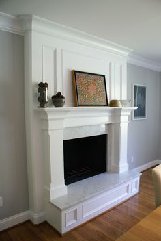 a white fireplace in a living room next to a dining room table with chairs and pictures on the wall