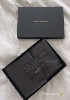 two black boxes sitting on top of a white bed next to each other with writing on them