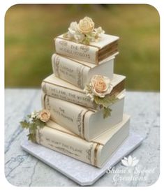 a stack of books sitting on top of a table next to flowers and greenery